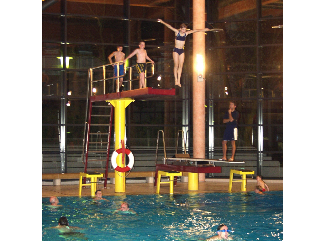 Foto zeigt Sprungtum 3 m und eine Springerin im Sprung, zwei weitere Badegäste warten bereits aus dem Sprungturm